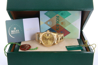 Gold Rolex watch with branded books and packaging.