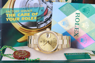 Gold Rolex watch with branded books and packaging.
