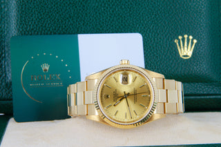 Gold Rolex watch with branded books and packaging.